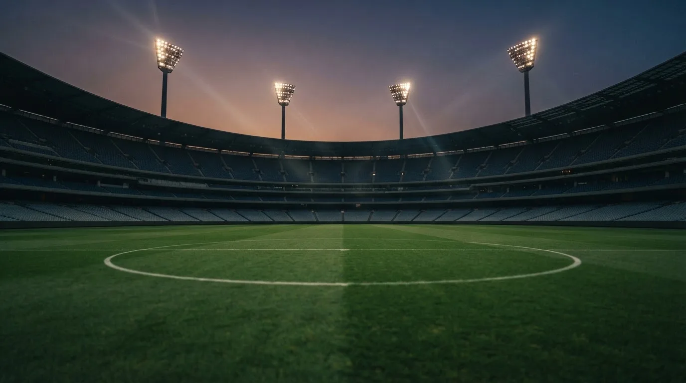 An empty football stadium with floodlight masts at dusk