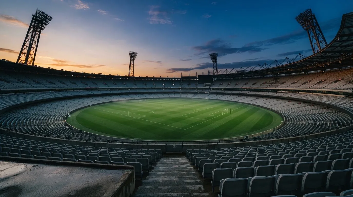 An empty football stadium with floodlight masts at dusk