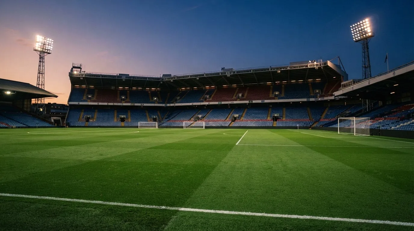 An empty football stadium with floodlight masts at dusk
