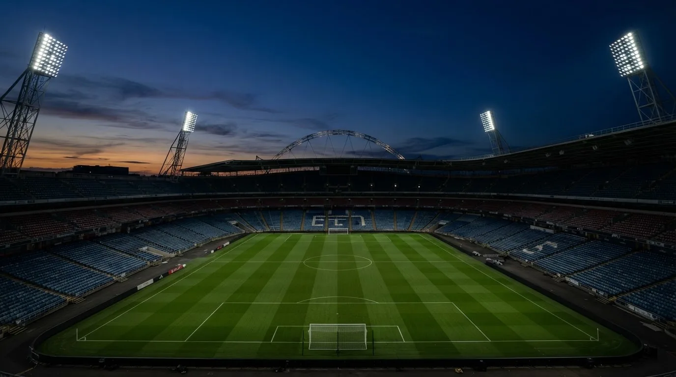 An empty football stadium with floodlight masts at dusk