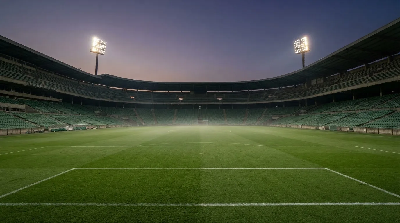 An empty football stadium with floodlight masts at dusk
