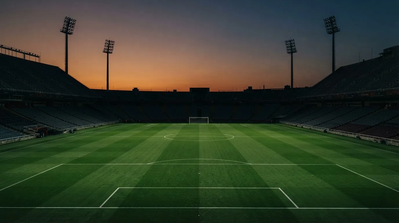 An empty football stadium with floodlight masts at dusk