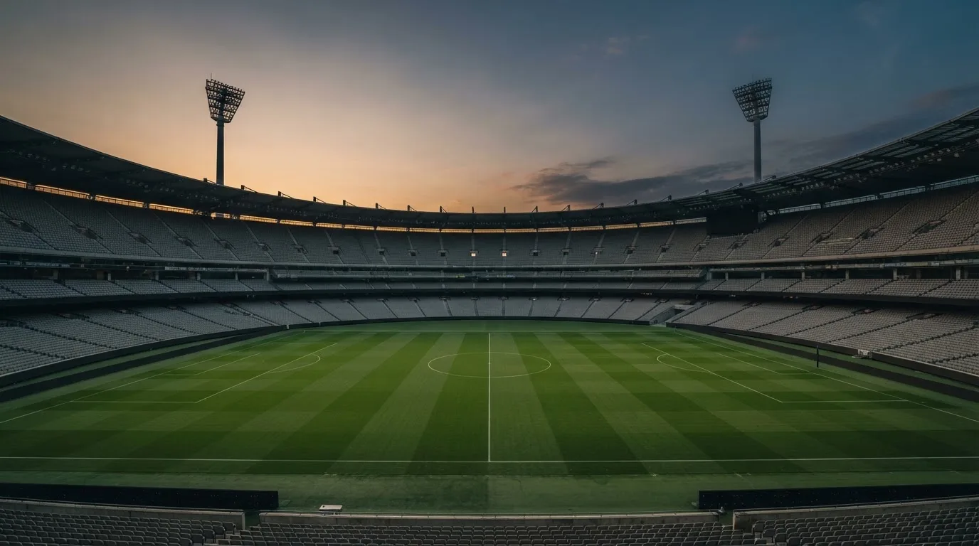 An empty football stadium with floodlight masts at dusk