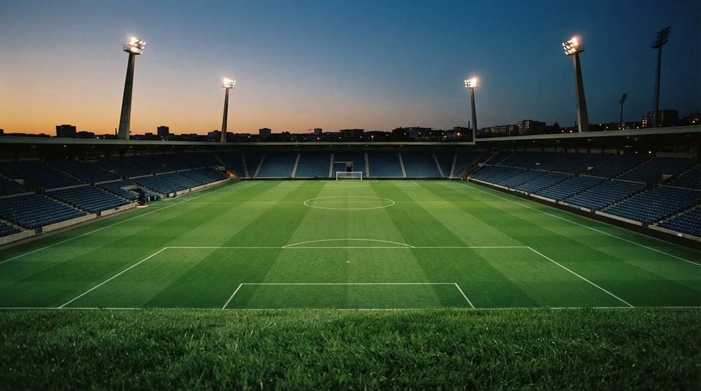 An empty football stadium with floodlight masts at dusk
