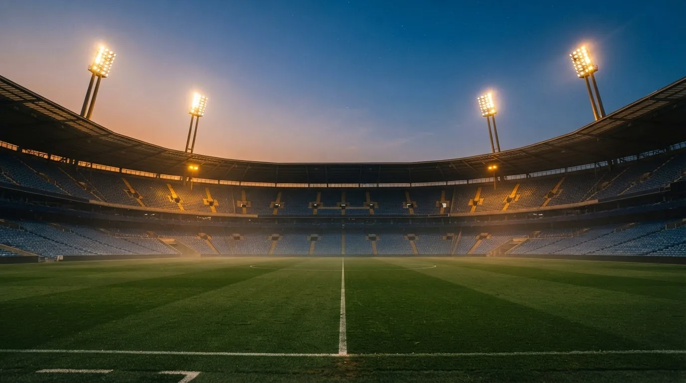 An empty football stadium with floodlight masts at dusk