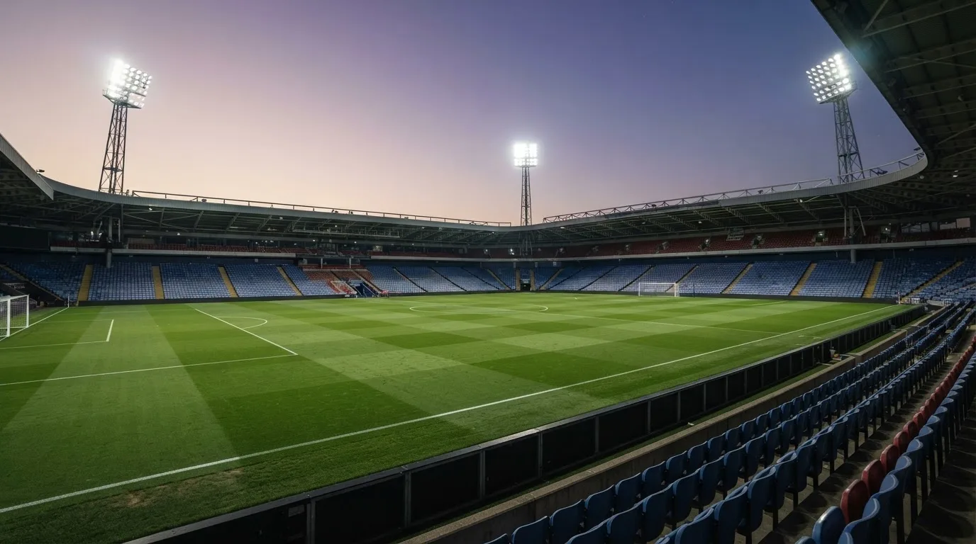 An empty football stadium with floodlight masts at dusk