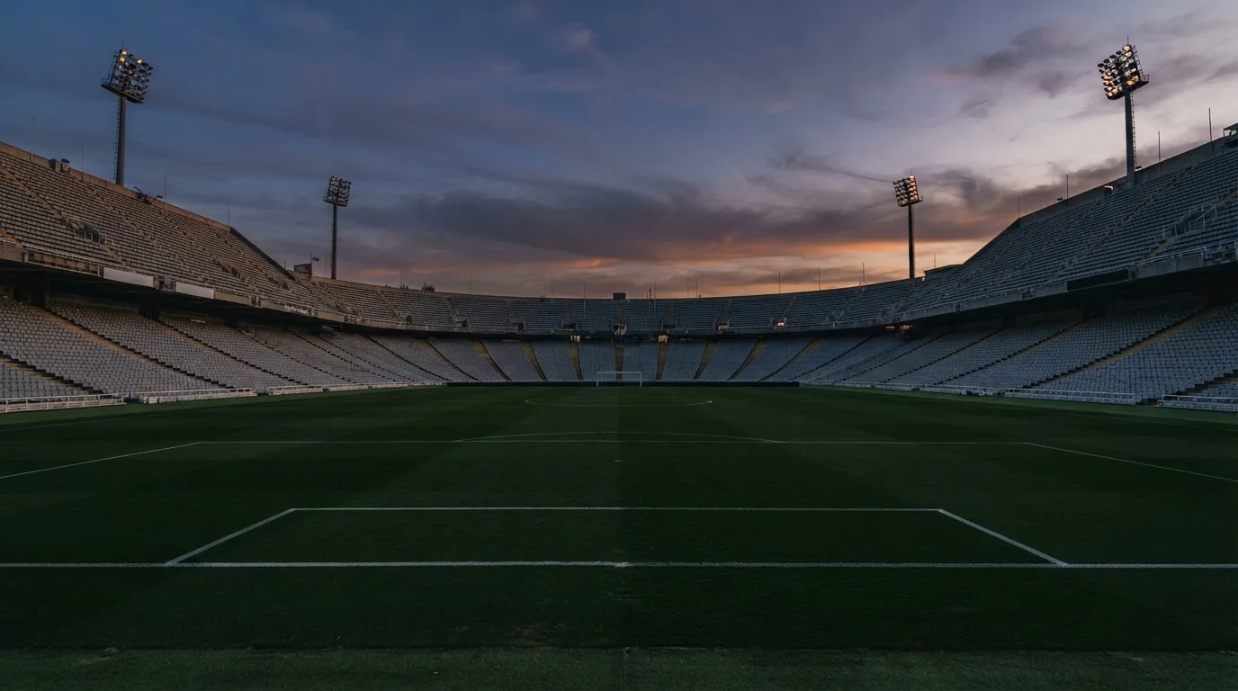An empty football stadium with floodlight masts at dusk