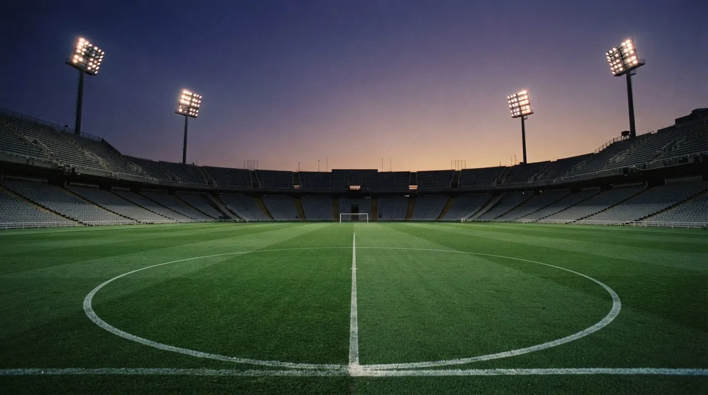 An empty football stadium with floodlight masts at dusk