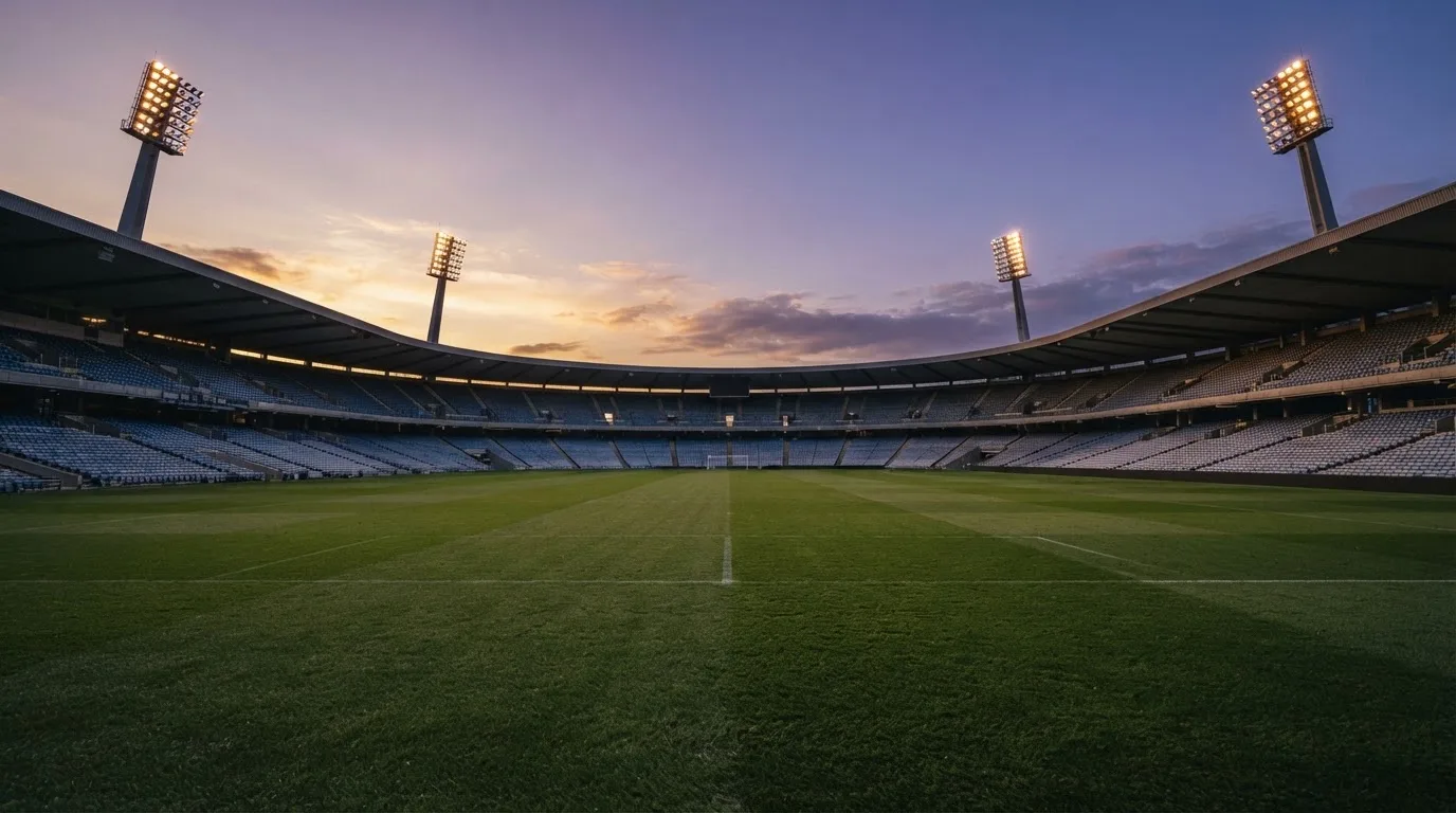 An empty football stadium with floodlight masts at dusk