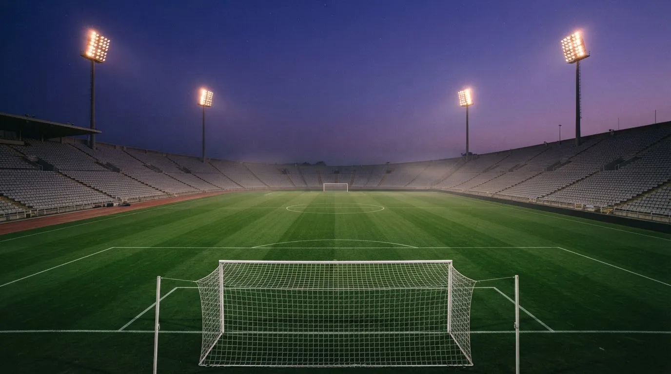 An empty football stadium with floodlight masts at dusk