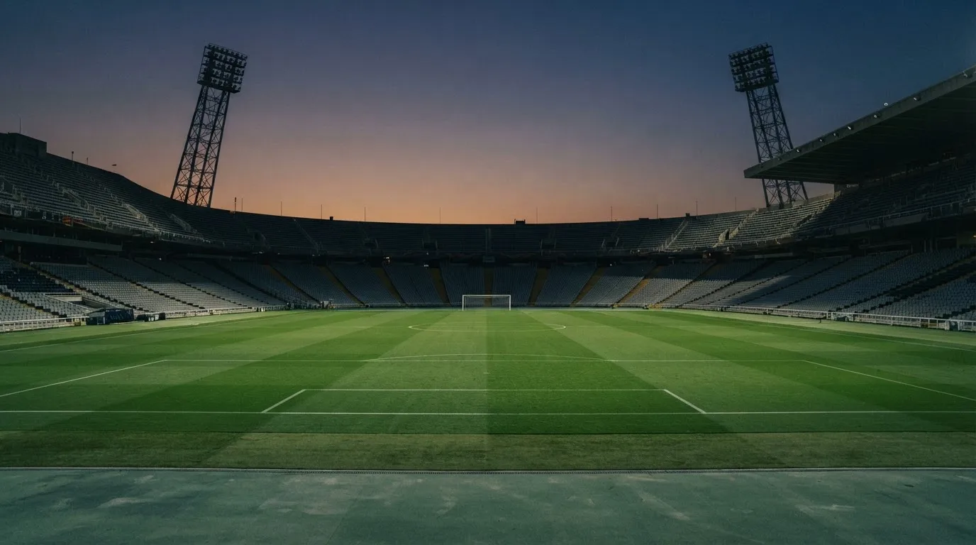 An empty football stadium with floodlight masts at dusk