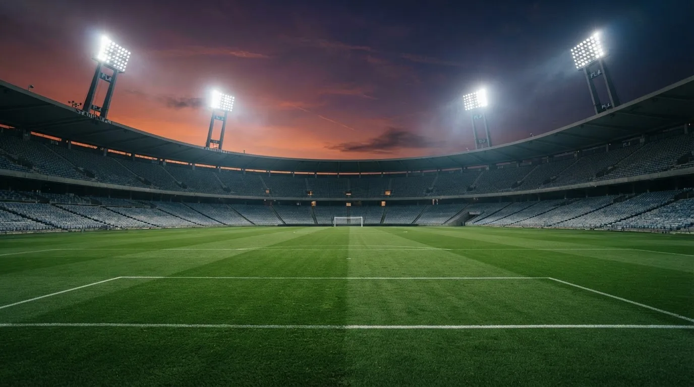 An empty football stadium with floodlight masts at dusk