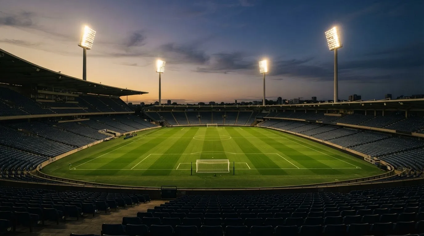 An empty football stadium with floodlight masts at dusk