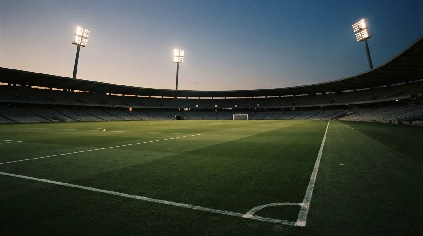 An empty football stadium with floodlight masts at dusk