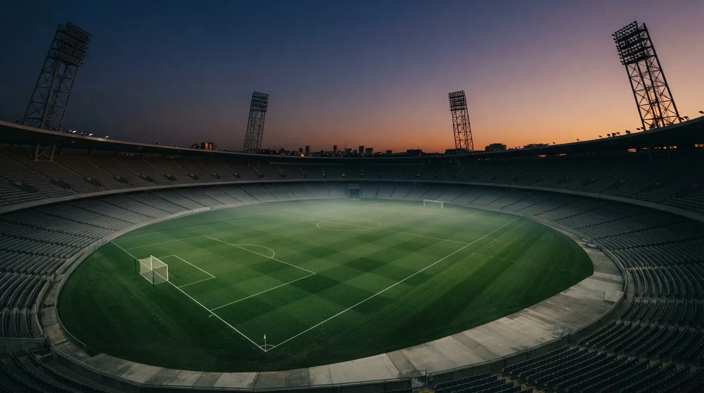 An empty football stadium with floodlight masts at dusk