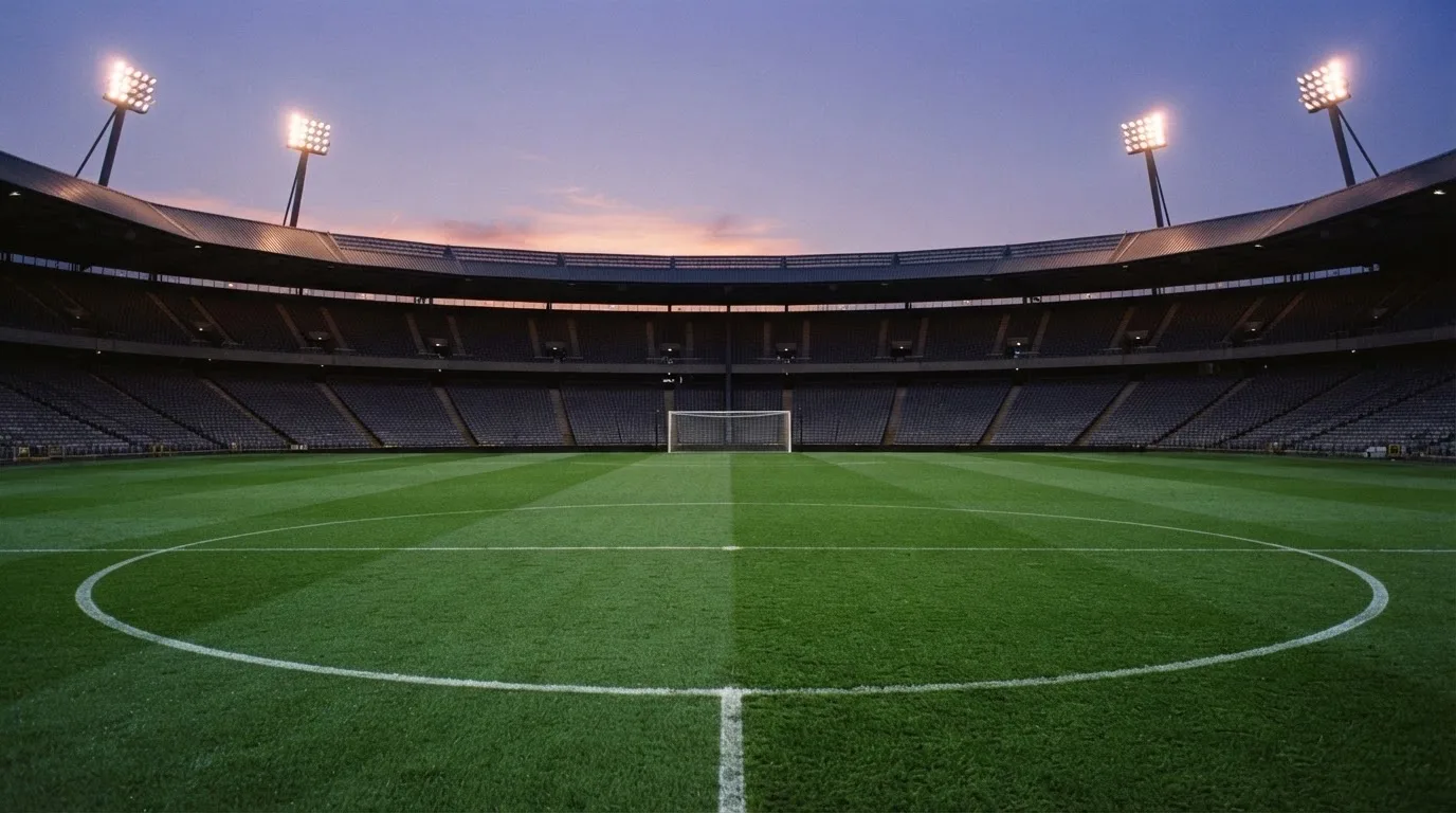 An empty football stadium with floodlight masts at dusk