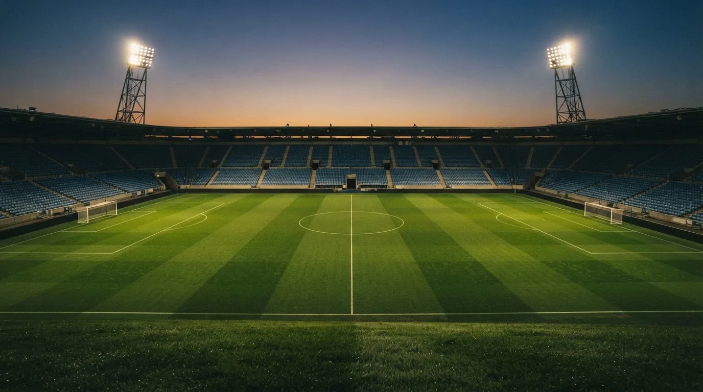 An empty football stadium with floodlight masts at dusk
