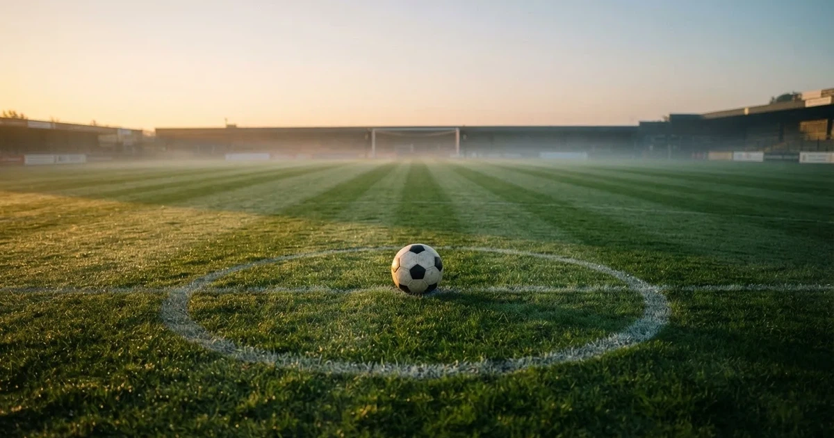 A ball on the centre spot of a grass pitch in morning light