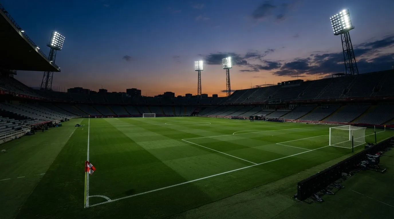 An empty football stadium with floodlight masts at dusk