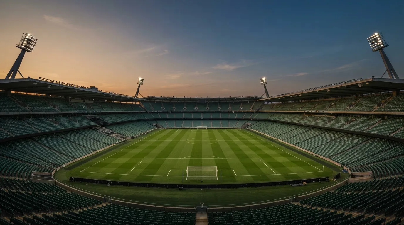 An empty football stadium with floodlight masts at dusk