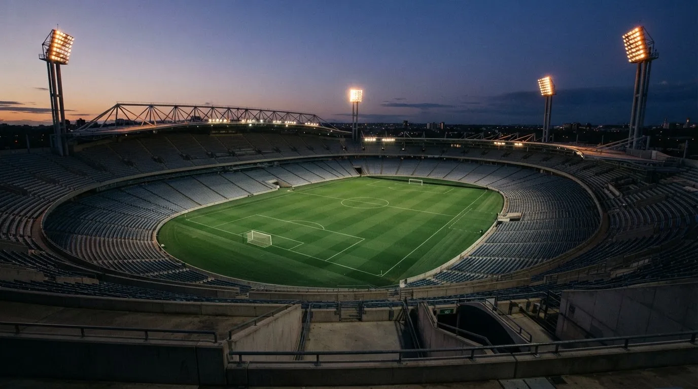 An empty football stadium with floodlight masts at dusk