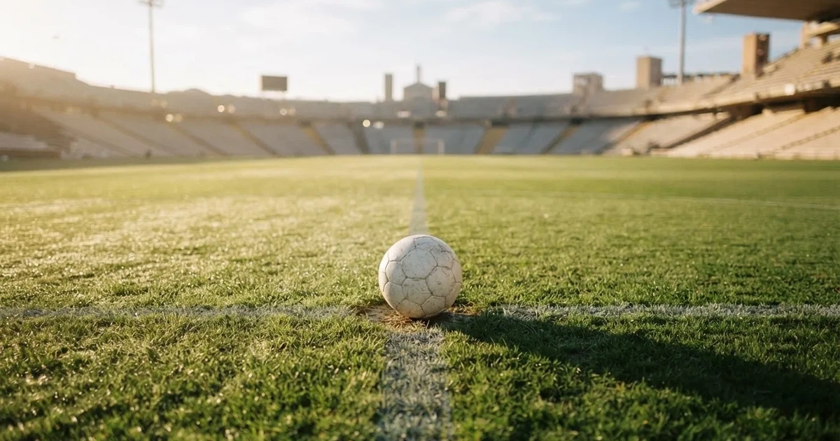 A ball on the centre spot of a grass pitch in morning light