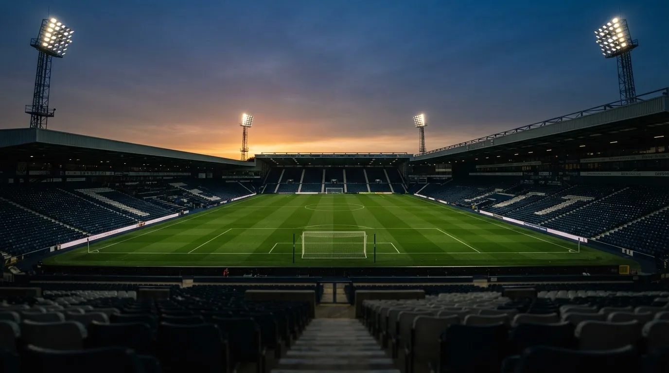 An empty football stadium with floodlight masts at dusk