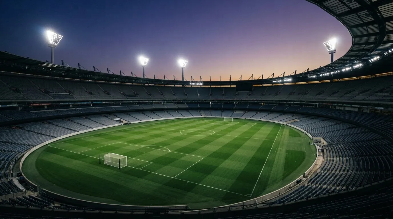 An empty football stadium with floodlight masts at dusk