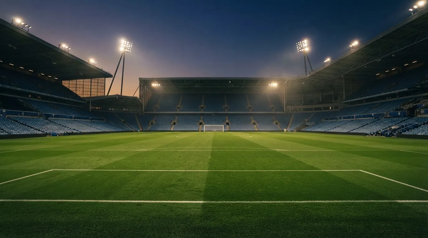 An empty football stadium with floodlight masts at dusk