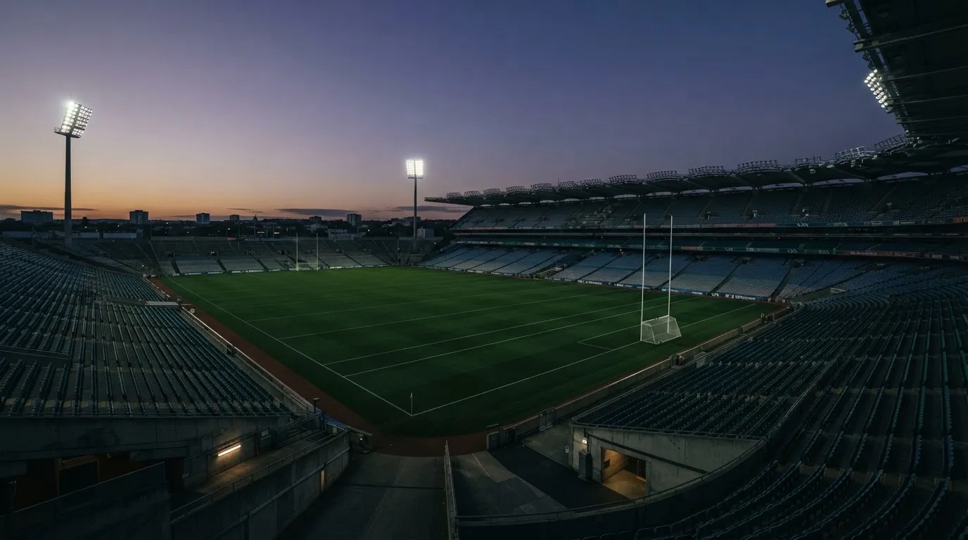 An empty football stadium with floodlight masts at dusk