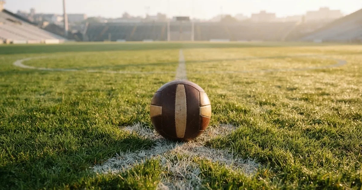 A ball on the centre spot of a grass pitch in morning light