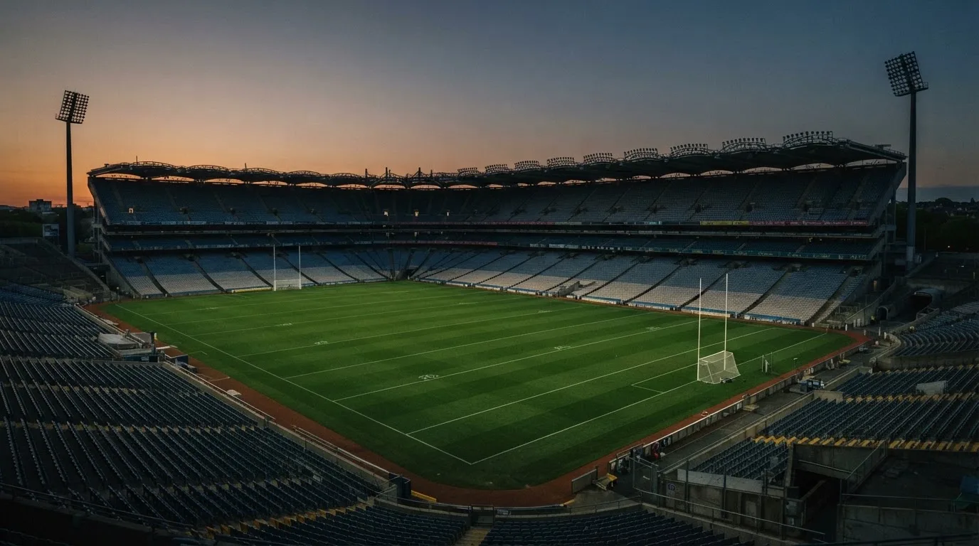 An empty football stadium with floodlight masts at dusk
