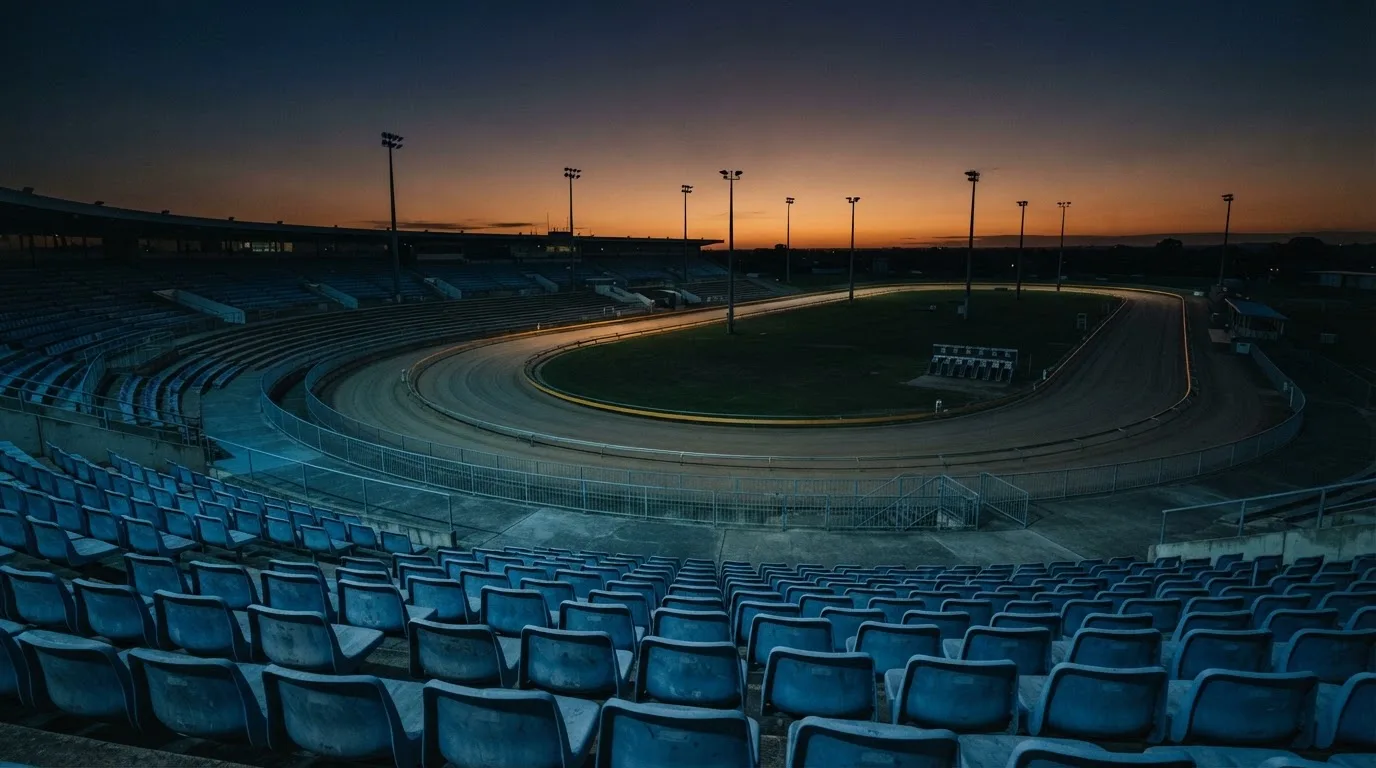 An empty football stadium with floodlight masts at dusk