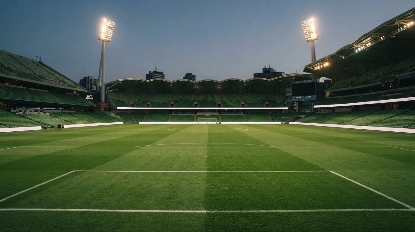 An empty football stadium with floodlight masts at dusk