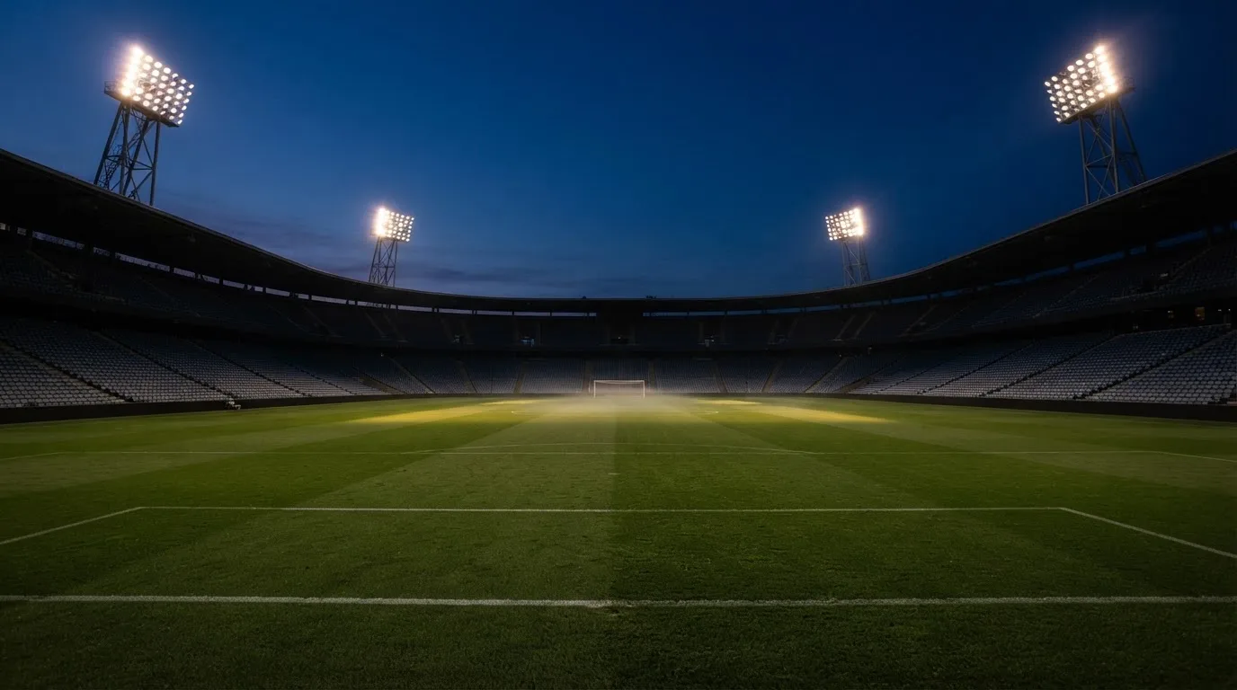 An empty football stadium with floodlight masts at dusk
