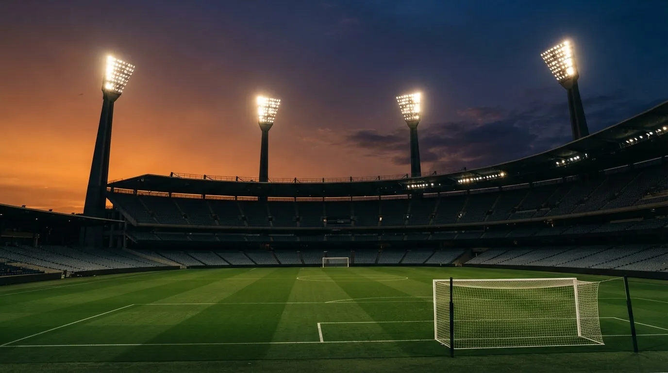 An empty football stadium with floodlight masts at dusk