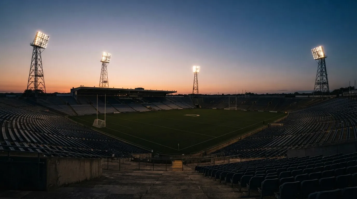 An empty football stadium with floodlight masts at dusk