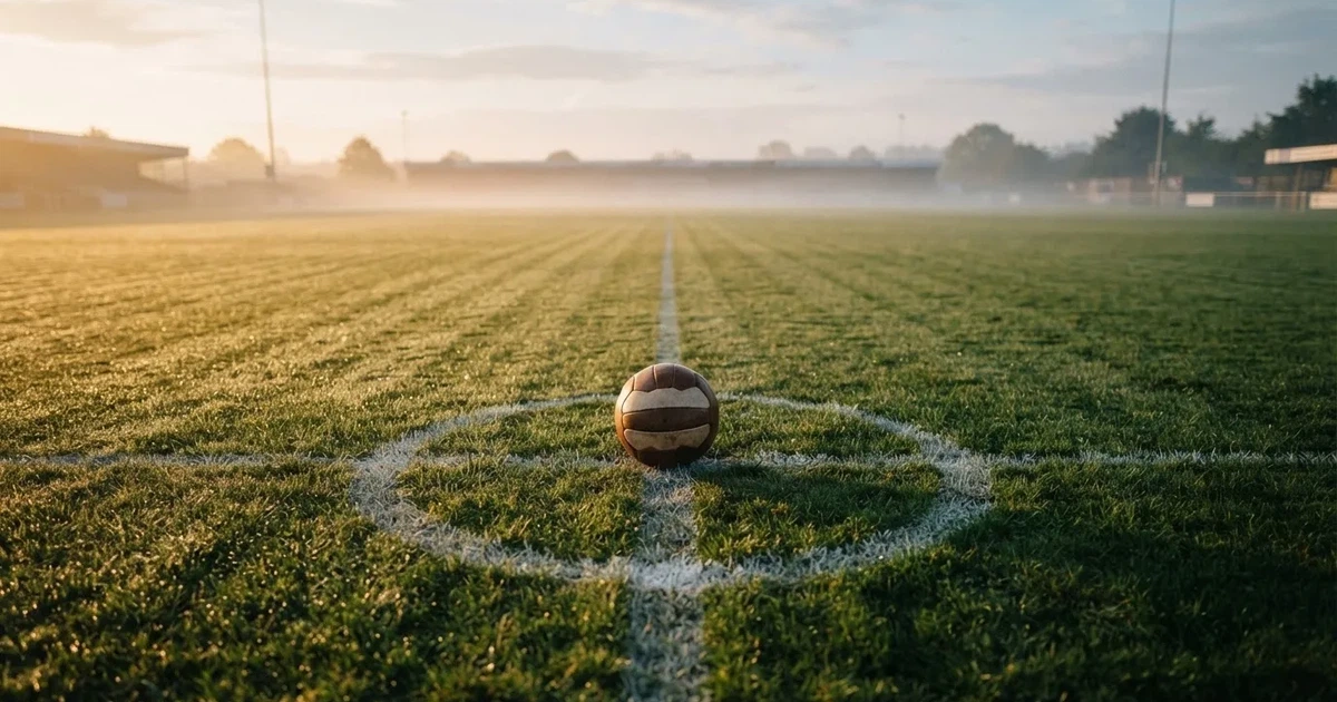 A ball on the centre spot of a grass pitch in morning light