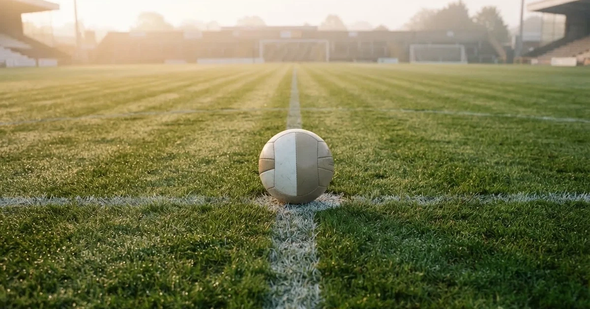 A ball on the centre spot of a grass pitch in morning light