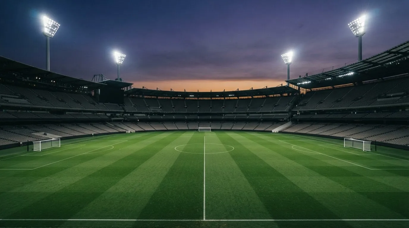 An empty football stadium with floodlight masts at dusk