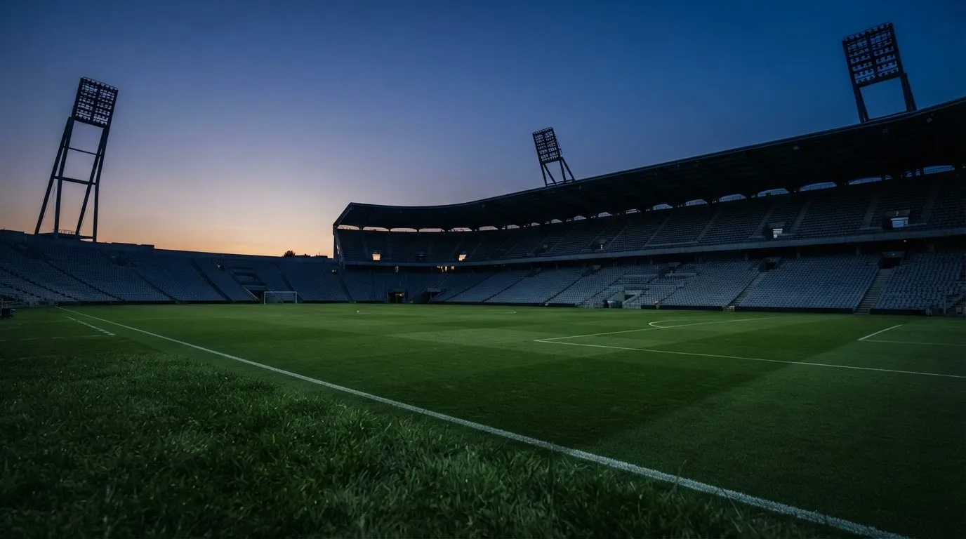 An empty football stadium with floodlight masts at dusk