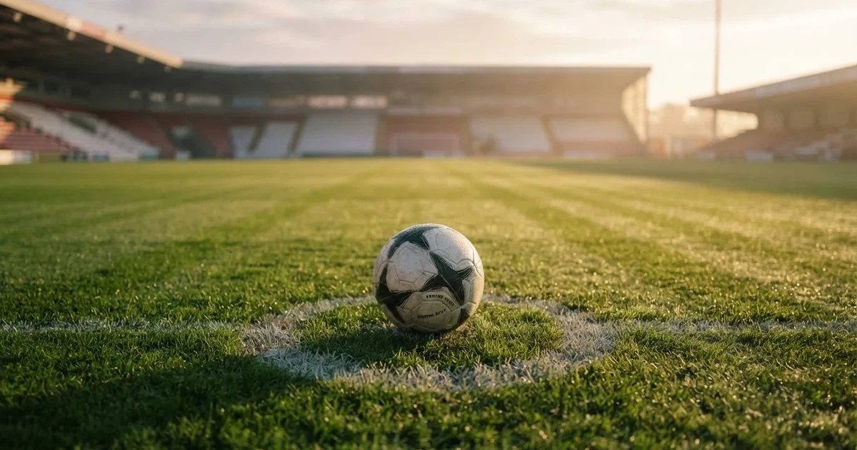 A ball on the centre spot of a grass pitch in morning light