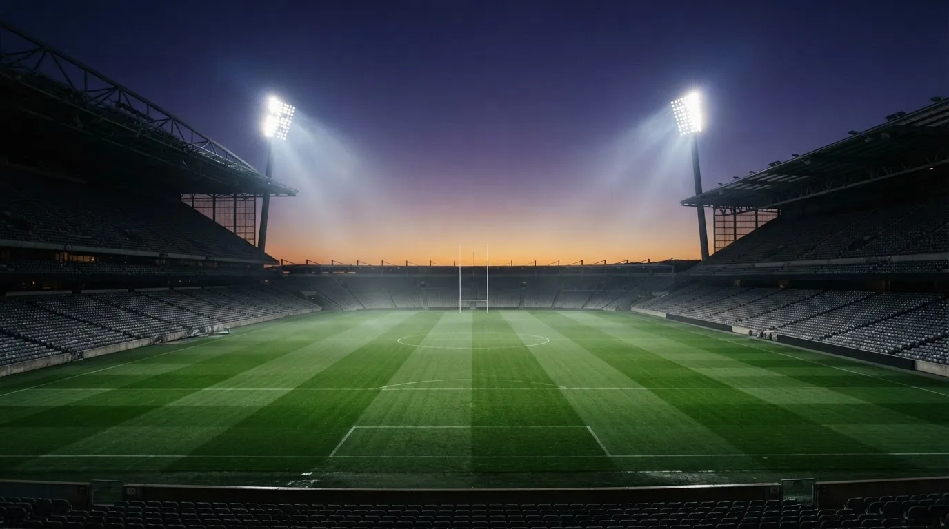 An empty football stadium with floodlight masts at dusk