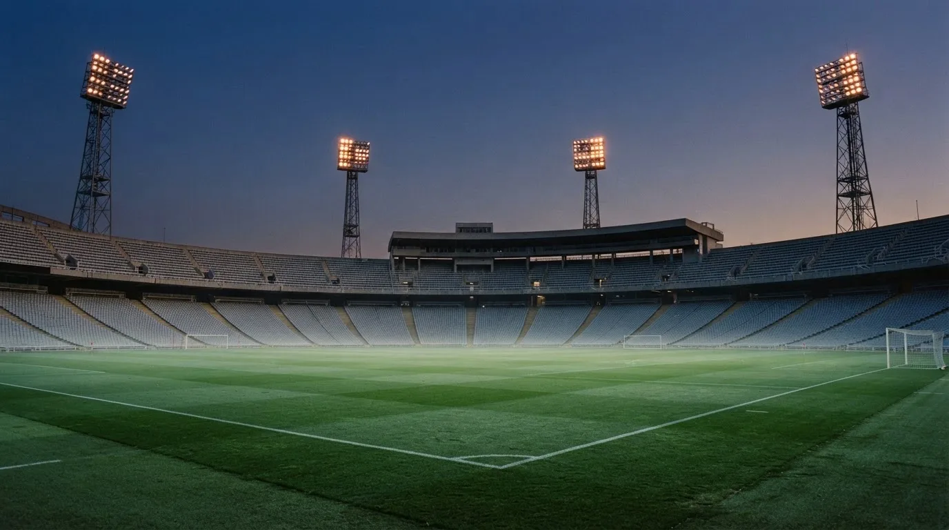 An empty football stadium with floodlight masts at dusk