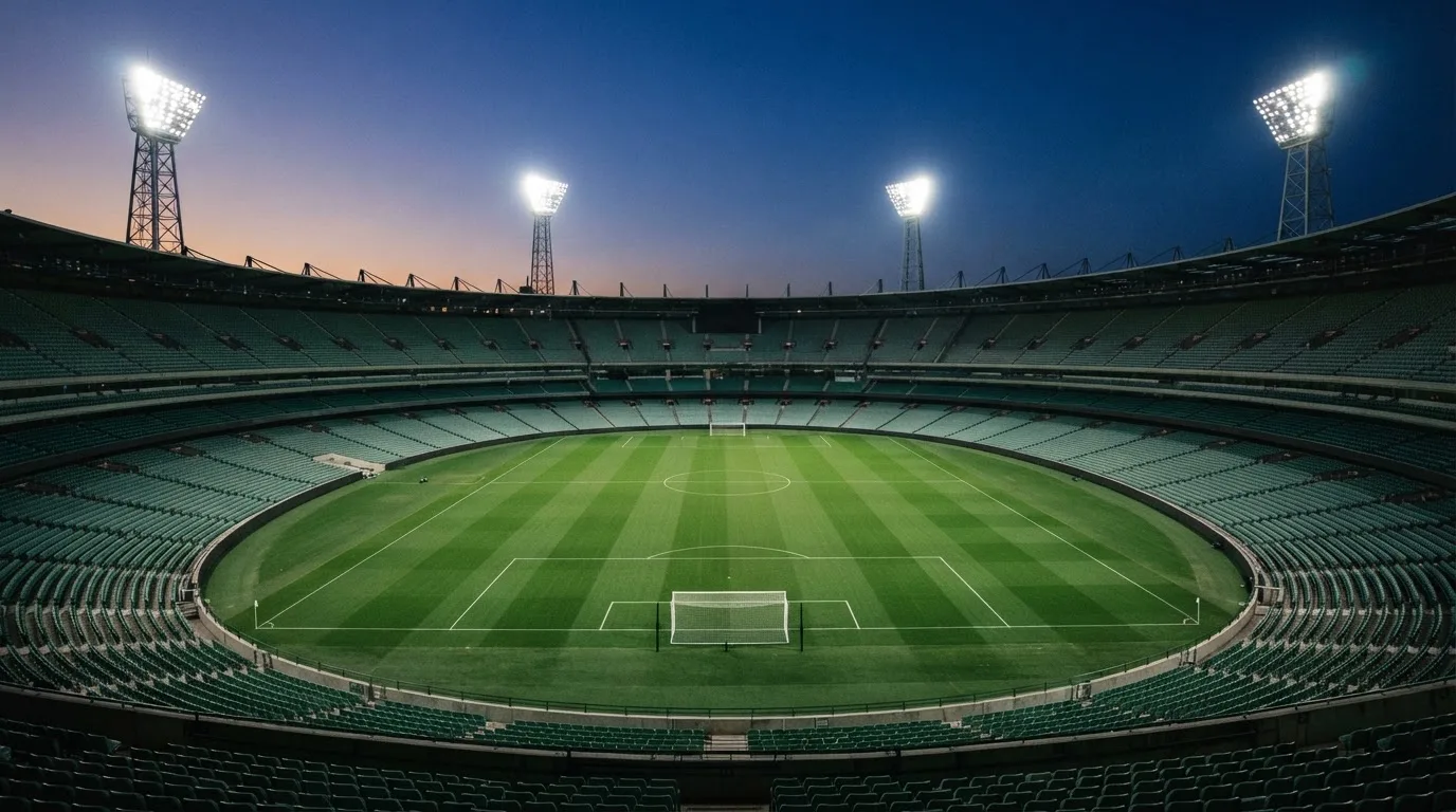 An empty football stadium with floodlight masts at dusk