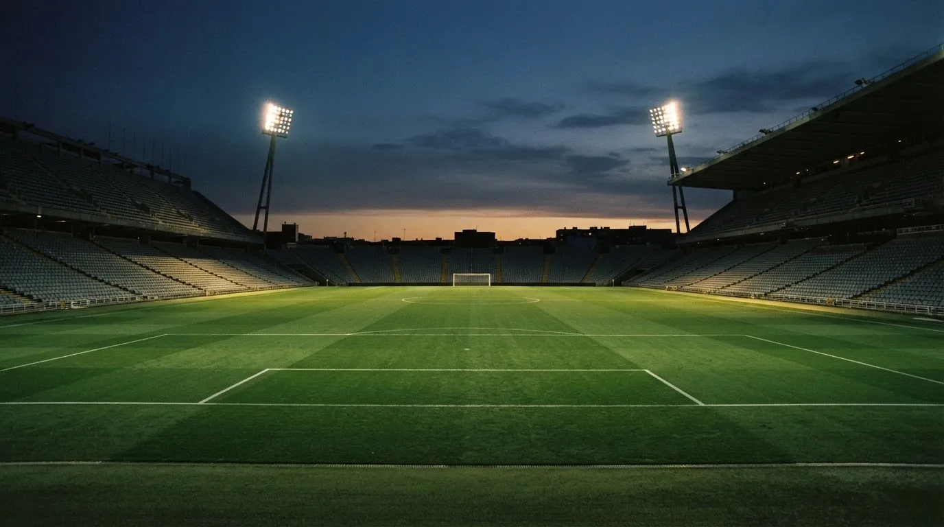 An empty football stadium with floodlight masts at dusk
