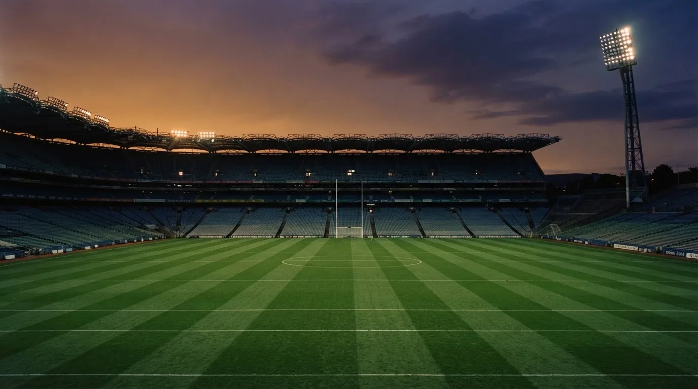 An empty football stadium with floodlight masts at dusk