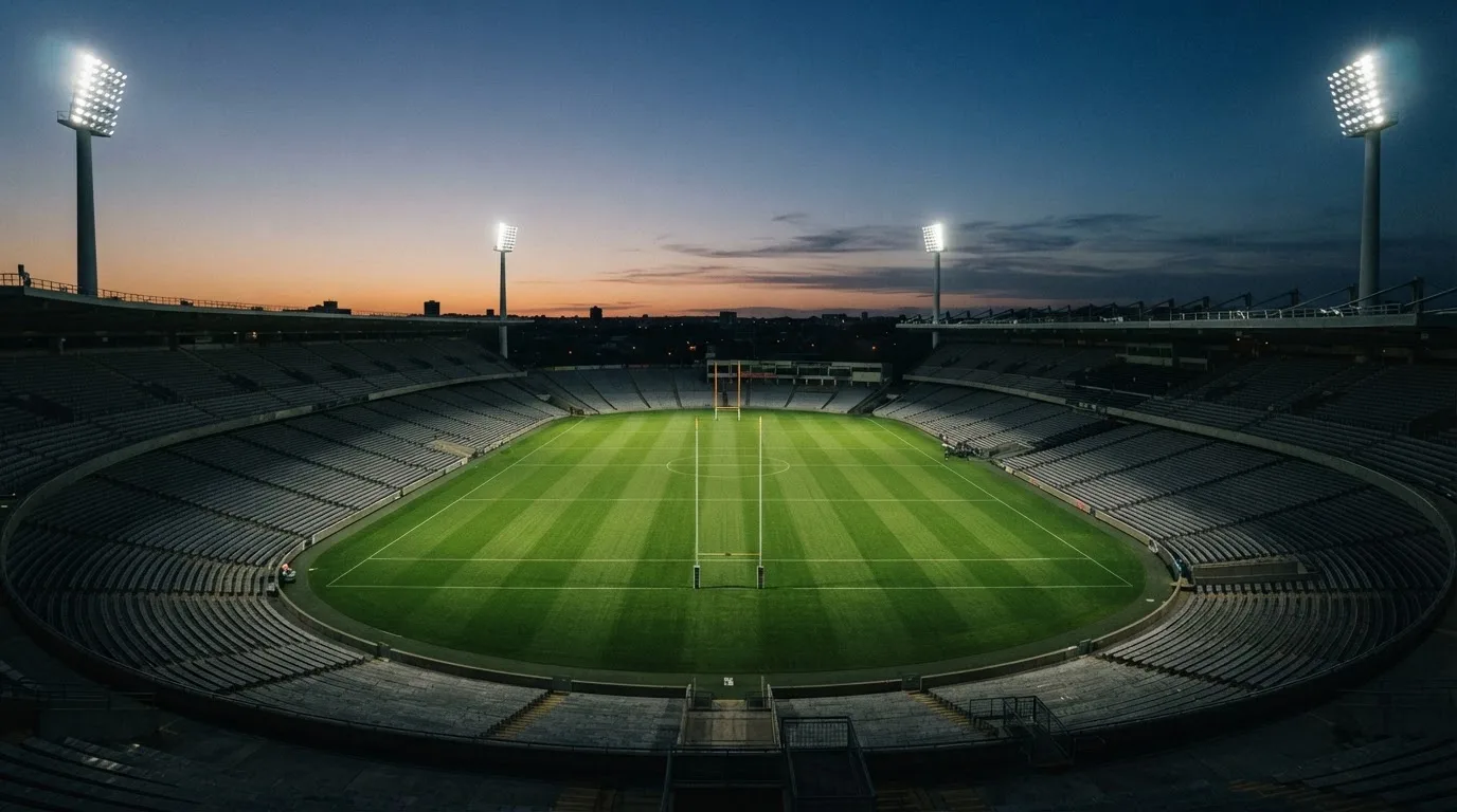 An empty football stadium with floodlight masts at dusk