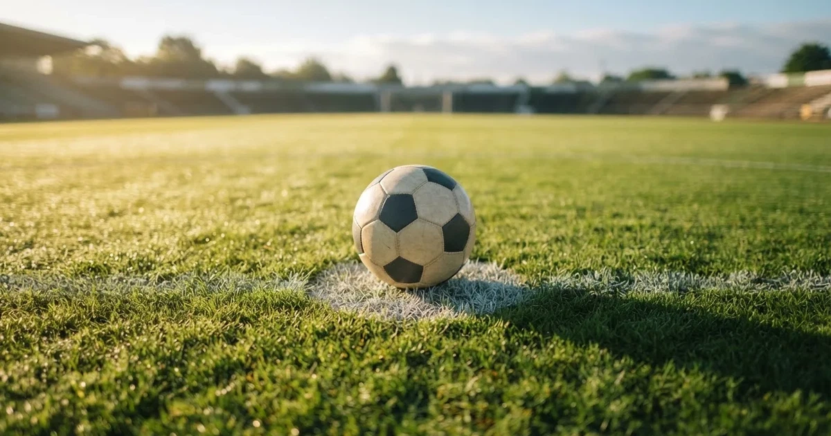 A ball on the centre spot of a grass pitch in morning light