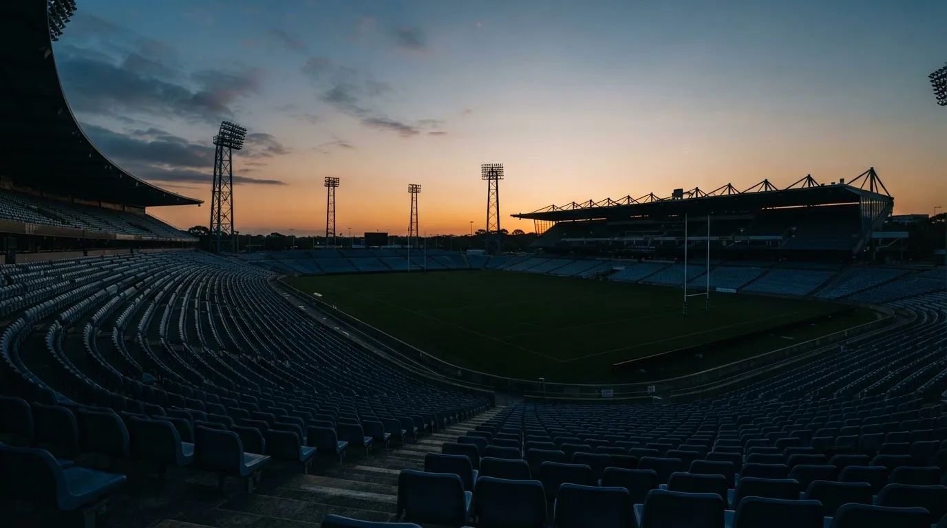 An empty football stadium with floodlight masts at dusk